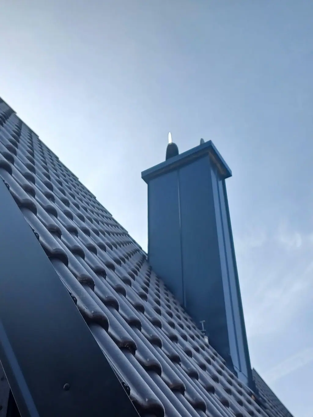 Kleparsko obrobljen dimnik na dokončani temni strehi