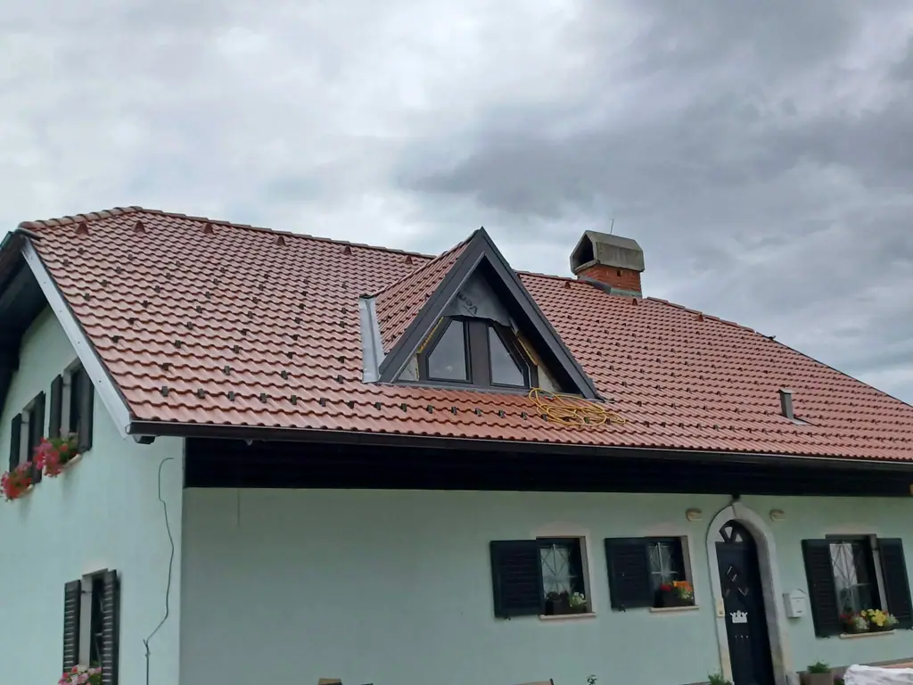 Hiša z novo opečno kritino in strešno frčado po zaključeni menjavi strehe