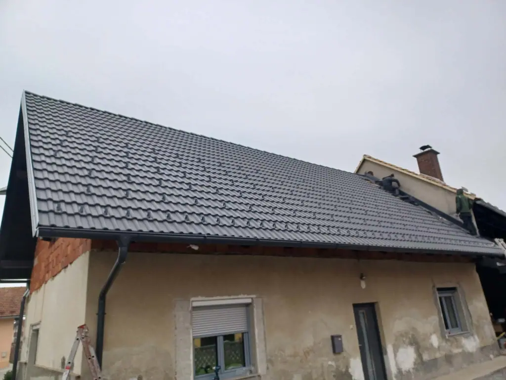 Starejša stanovanjska hiša z novo temno kritino po sanaciji strehe